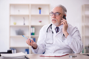 Old male doctor in telemedicine concept