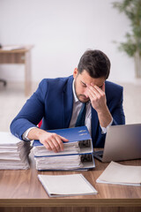 Young male employee and too much work in the office