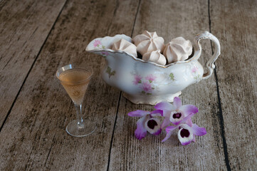 Meringues in a vase and a glass of champagne on a wooden background