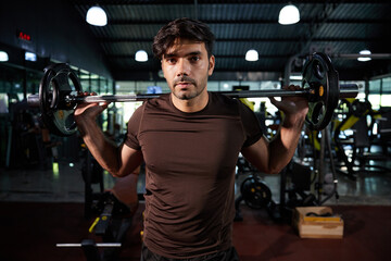 Fototapeta na wymiar young athletic man exercising with barbell in the gym