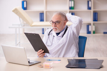 Obraz premium Old male doctor working in the clinic