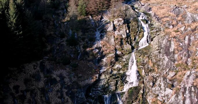 A pull back Aerial view of the Glenmacnass Waterfall falling 80 meters down the valley of the Glenmacnass river in the Wicklow Mountains near Laragh  flowing into  the sea at Arklow near tR115 road.