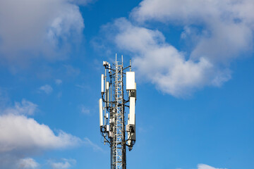 Two telecommunication towers with 4G, 5G transmitters. Cellular base stations with transmitting antennas on a telecommunication tower on a background of blue sky with pink-yellow clouds. Tinted