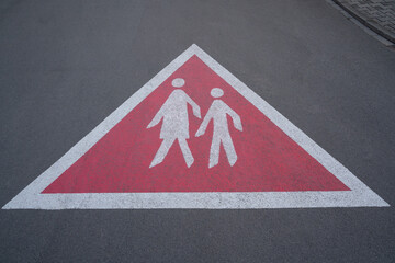 Triangular warning sign on the paved road showing walking pedestrians. So that drivers drive carefully and watch out for pedestrians.