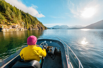 Woman Driving Motor Boat in Amazing Nature Landscape at Sunset in Coastal British Columbia Near Bute, Toba Inlet and Campbell River. Whale Watching Tourist Travel Destination, Canada - obrazy, fototapety, plakaty