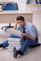 Young male employee unhappy with excessive work in the office