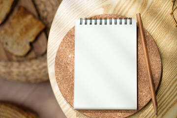 mockup blank sprial notebook top view on wood table with morning sunlight