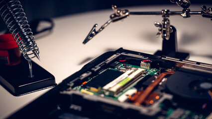 a computer master solders a chip and a board on a laptop, the concept of electronics repair shops