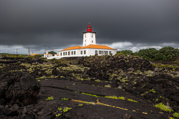 Fototapeta na wymiar Dark clouds over the lighthouse on the lava coast 