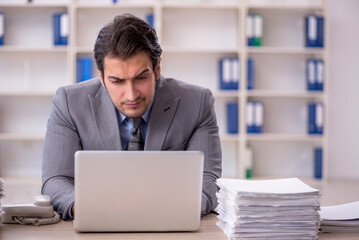 Young male employee and too much work at workplace