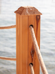 Wooden pole of a rope fence near the sea