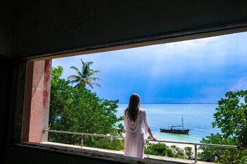 woman looking out window in abandoned hotel of Santa Carolina Island in Mozambique