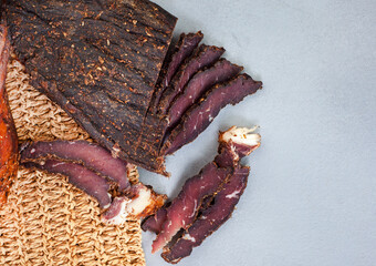 Freshly cut South African biltong with selective focus on grey surface with woven place mat