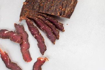 Deurstickers Freshly cut South African biltong on light background with selective focus and copy space. © Aninka