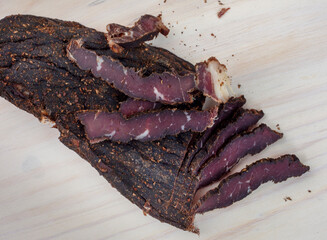 Freshly cut South African biltong with selective focus on light wooden surface