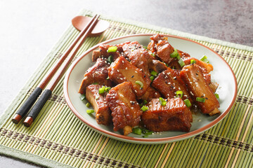 Barbecue sweet and sour spire ribs with green onion and sesame close-up in a plate on the table. Horizontal