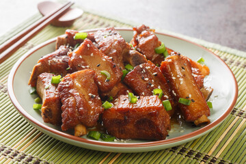 Glazed pork short ribs in sweet and sour sauce in Asian style close-up in a plate on the table....