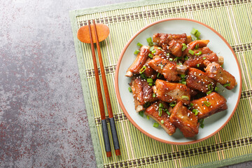 Glazed pork short ribs in sweet and sour sauce in Asian style close-up in a plate on the table. horizontal top view from above