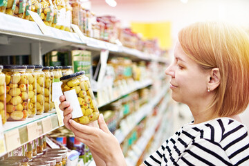 Jar of olives with vegetables in hands woman in shop