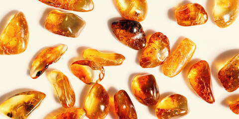 Natural gemstones of amber as background, transparent stones yellow orange colors. Natural rocks beige monochrome. Top view Amber textured gems. Aesthetic wallpaper, banner with uncut stones.