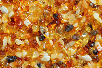 Natural gemstone amber texture background, small stones yellow orange gradient color. Natural mineral material for jewelry. Top view Amber texture. Aesthetic wallpaper, pieces ancient resin.
