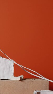 Vertical studio shot footage of trendy still life composition made of gypsum, brick and dried plant branches, terracotta background
