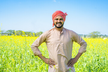 Portrait shot of Happy young farmer confidently standing by looking camera at farmland - concept of...