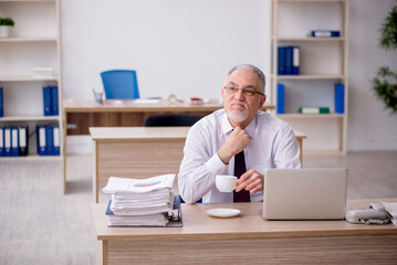 Old male employee drinking coffee during break