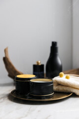 Soy scented candles in metal jars, boxes. Candles on a metal tray. in front of a bathtub. Modern hobby handmade, paraffin free coconut wax candles. Wooden wick. 