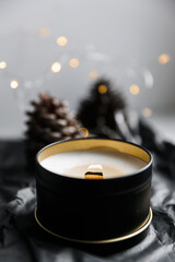 Soy scented candles in metal tins, boxes. Candles on the table in the room with a backdrop of pinecone and Christmas lights.  Modern handmade coconut wax candles without paraffin. burns Wooden wick. 