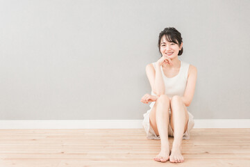 Fototapeta premium 家のリビングに座る美人のアジア人女性（美容・ダイエット・エステ・脱毛・美脚・スキンケア・カメラ目線） 