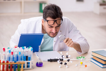 Young male chemist sitting at the lab