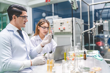 Young male and female scientist in lab coat wearing protective eyeglasses and rubber gloves while working on science experiment and research in modern laboratory using test tubes and equipment