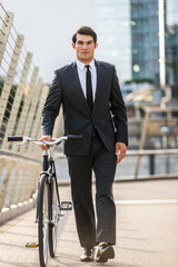 Young handsome man with business suit driving bicicyle to go to office - Corporate businessman portrait biking in the city, concepts about business, green mobility and lifestyle