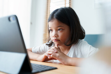 Boring asian little girl using tablet digital at home - 566520599