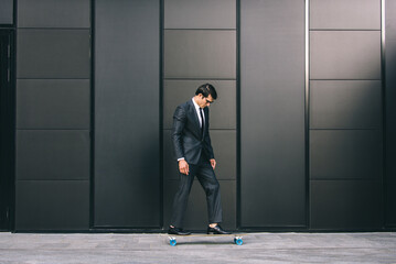 Fototapeta na wymiar Young handsome man with business suit riding on a longboard - Corporate businessman portrait, concepts about business, mobility and lifestyle