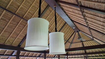 linen shaded hanging lamp under bamboo roof