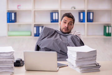 Fototapeta premium Young male employee unhappy with excessive work in the office