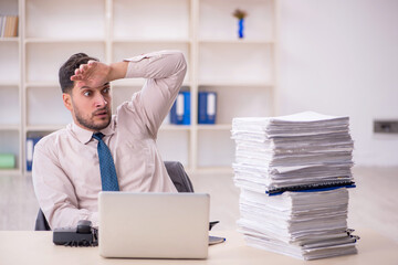 Young male employee unhappy with excessive work in the office