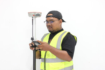 An asian male land surveyor operates a GNSS tool that is used to measure land with a satellite...
