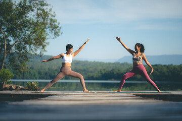 Two beauty woman doing yoga on morning park, Yoga training strong woman best friends doing yoga at mountain, dressed in sportswear, woman practicing yoga in Pose Dedicated