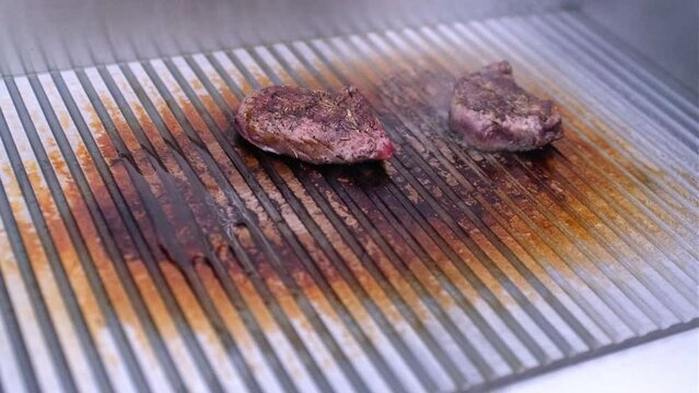 2 Steaks von einem Lamm auf elektrischem Grill. Der Grill hat eine Temperatur von 300 Grad. Eine M&auml;nner Hand wendet das Fleisch. &Ouml;l beginnt zu brutzeln. Echtzeit und Sound.