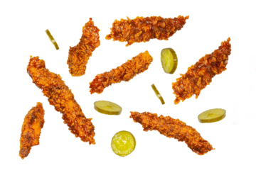 Fried chicken breast fillet strips in different angles flying with jalapeño pickles isolated on white with clipping mask.