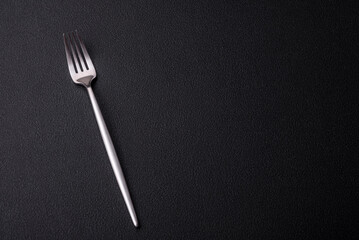 Metal kitchen fork on a dark textured concrete background