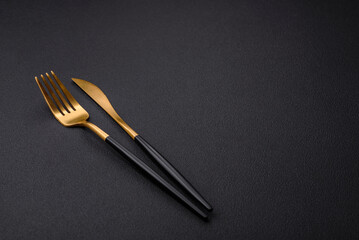 Metal kitchen knife and fork on a dark textured concrete background