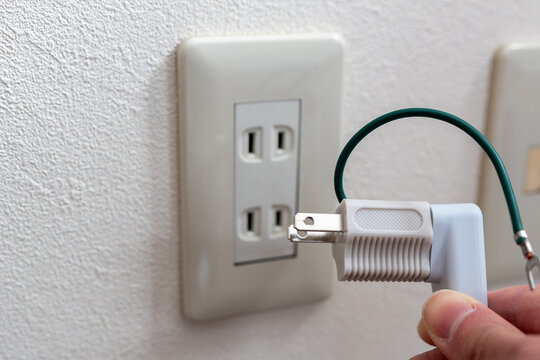 A Japanese wall socket without earth post. 3 pins power plug connected to a travel adapter.