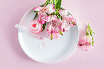 top view of an open matte cosmetic bottle and a filled pipette with a natural facial skin care product. additional care. pink background.