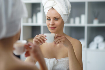 Young woman sits in the bathroom in front of the makeup mirror and does cosmetic procedures....