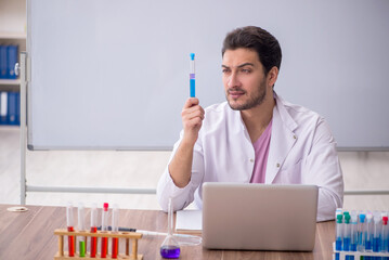 Young male chemistry teacher sitting in the classroom