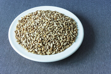 View of unshelled sunflower seeds in a plate on a tablecloth